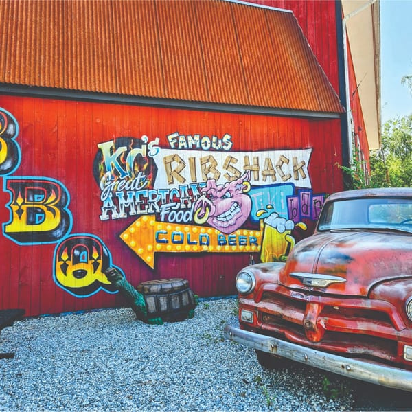 KC's Rib Shack exterior with a red barn, graffiti, and a vintage red truck.