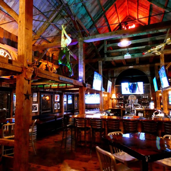 Rustic KC's Rib Shack interior with wooden beams, a bar, tables, and a mermaid sculpture.