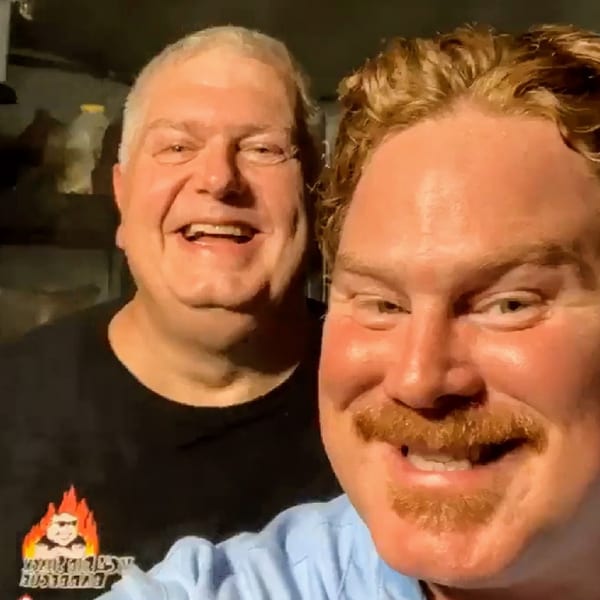 Two smiling men, one with a KC's Rib Shack logo shirt, posing for a photo.
