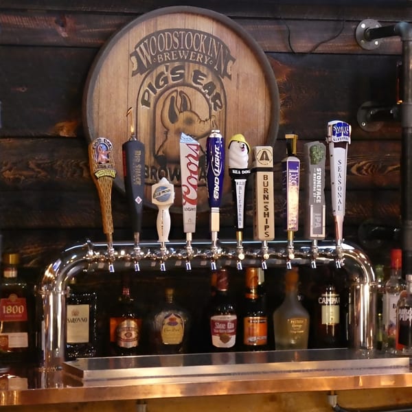 A row of beer taps and liquor bottles at KC's Rib Shack bar, with a wooden barrel sign.