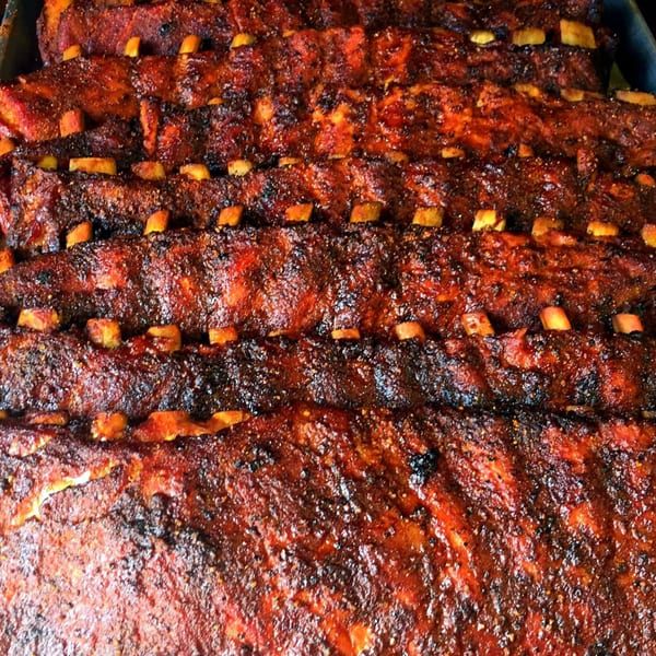 Close-up of several racks of KC's Rib Shack BBQ ribs, glistening with sauce and seasoning.
